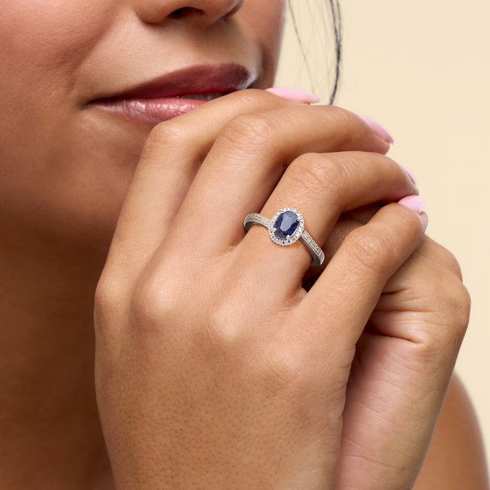 Sterling silver oval sapphire ring with diamond halo on finger