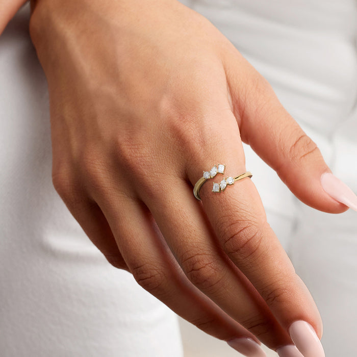 Gold bypass diamond ring on hand with lab-grown round and baguette stones