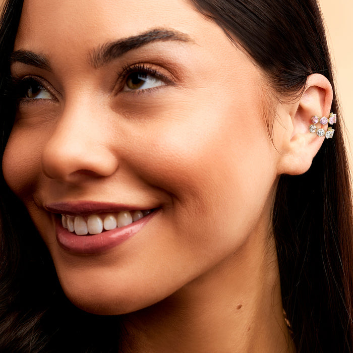 Gold-tone ear cuffs with pink simulated gemstones on model, close-up