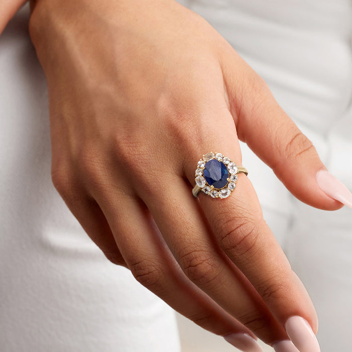 Sapphire and white crystal halo ring in gold on hand