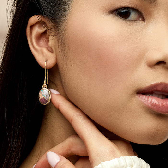 Turquoise oval drop earring on gold earwire worn on ear