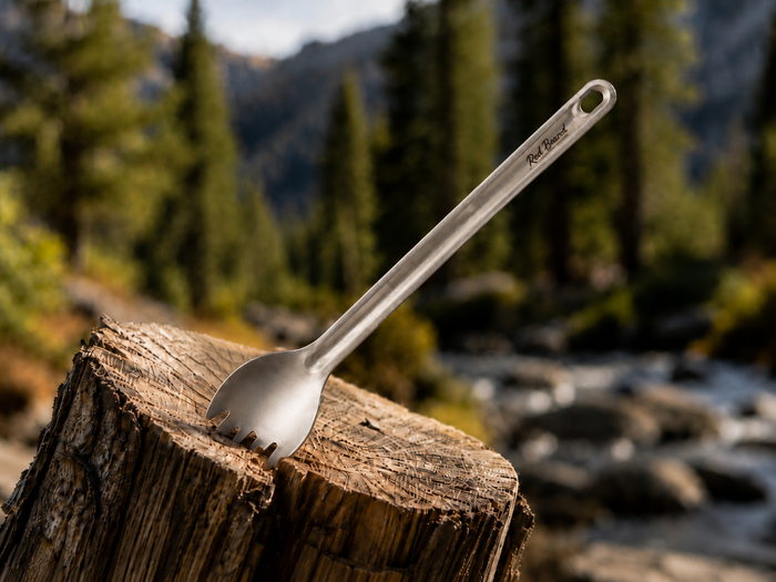 Red Beard’s Outfitter long handle titanium spork displayed outdoors beside a mountain stream