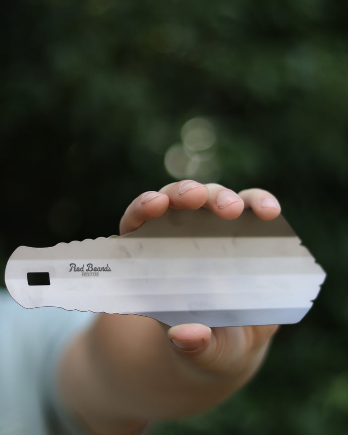 Sas-Squat titanium backpacking trowel held in one hand outdoors