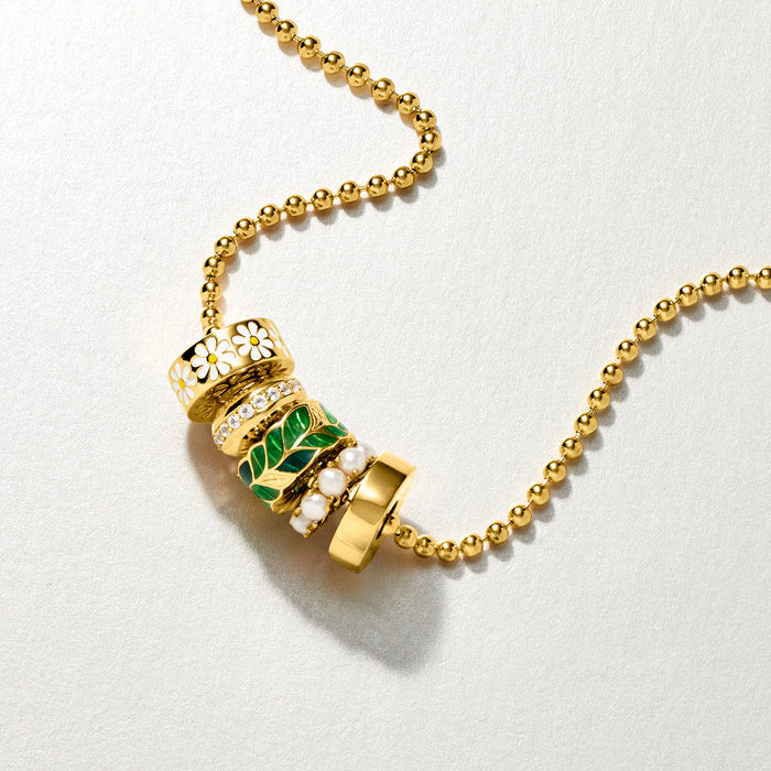 Gold-tone enamel bead charm with green and white pattern and small stone accents